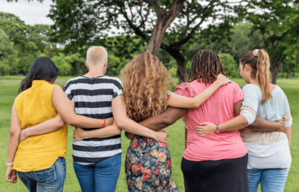 5 women facing away with arms around each other friends