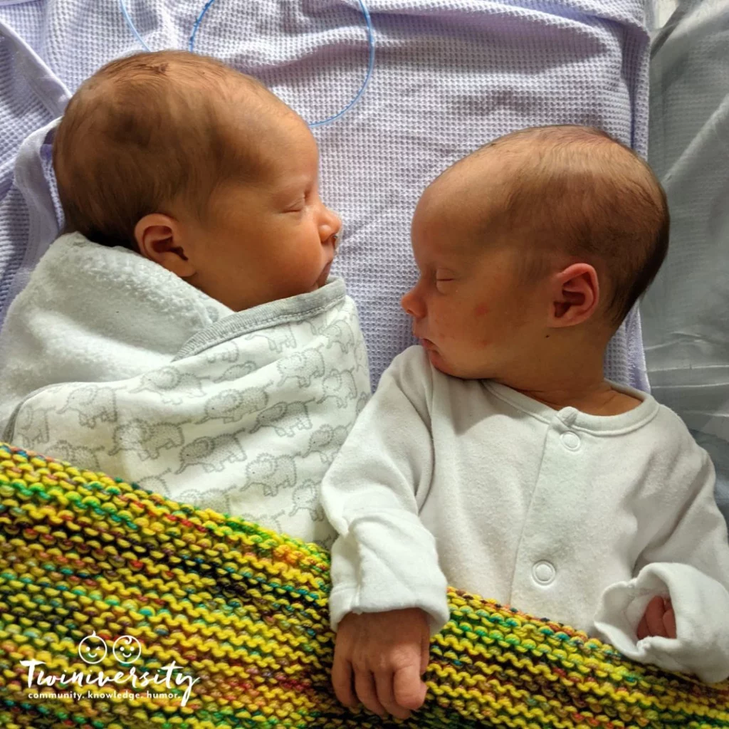 Two newborn babies sleeping in the same bassinet