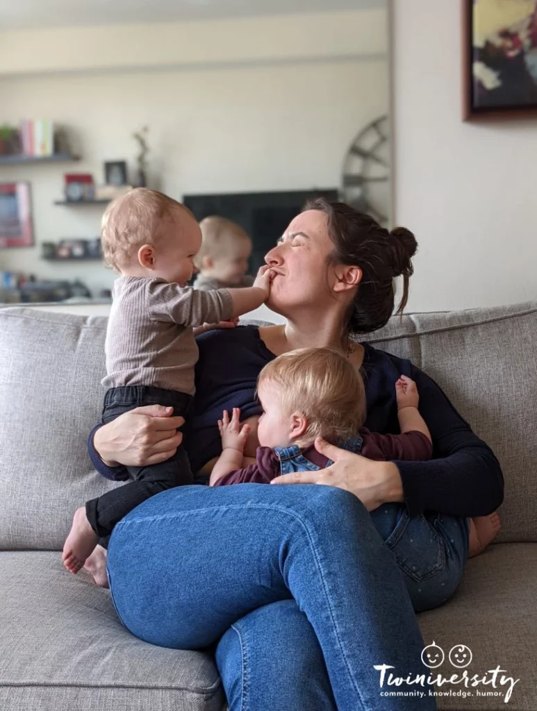 Twin mom sitting on a couch holding both twin girls