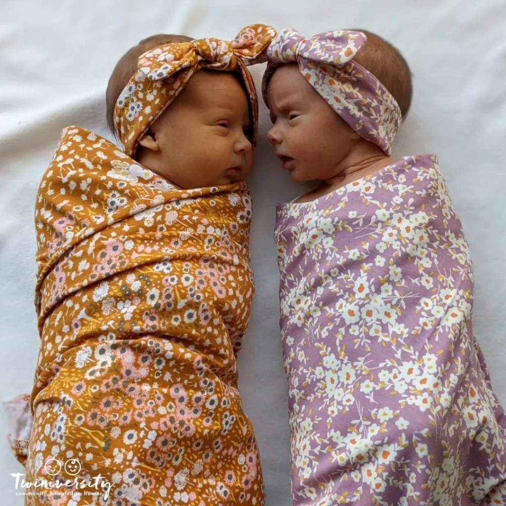 Twin baby girls, swaddled in floral blankets wearing matching headbands