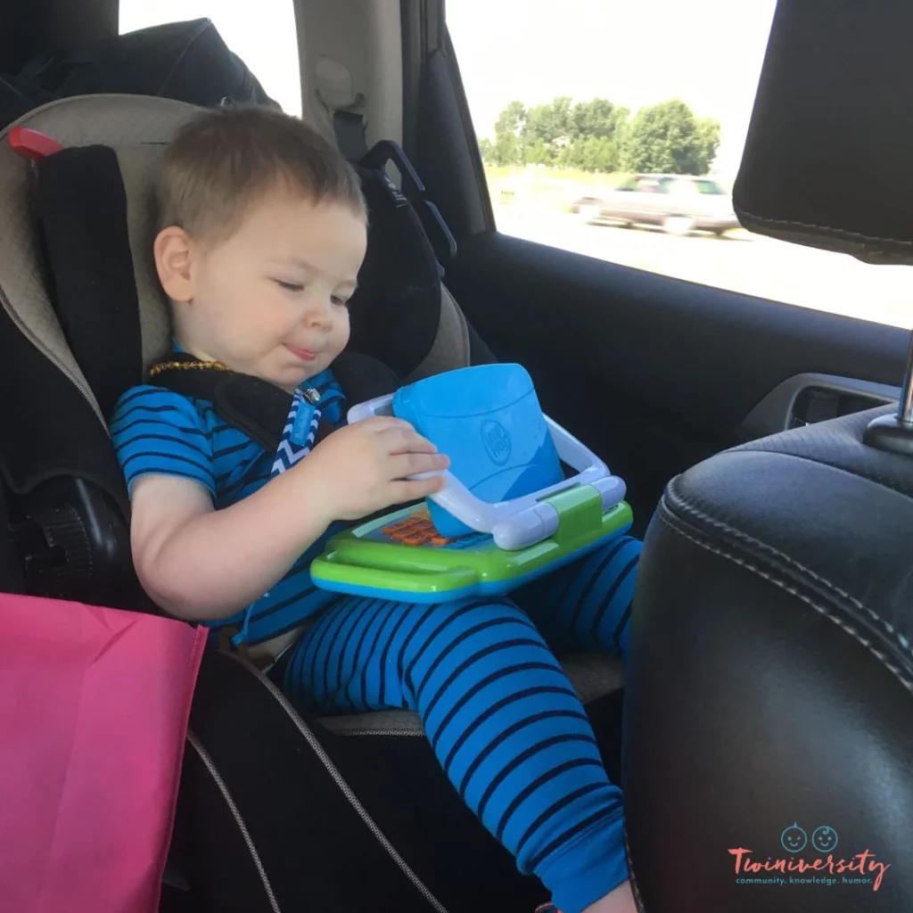 Toddler in car seat wearing pajamas and playing with a toy. 