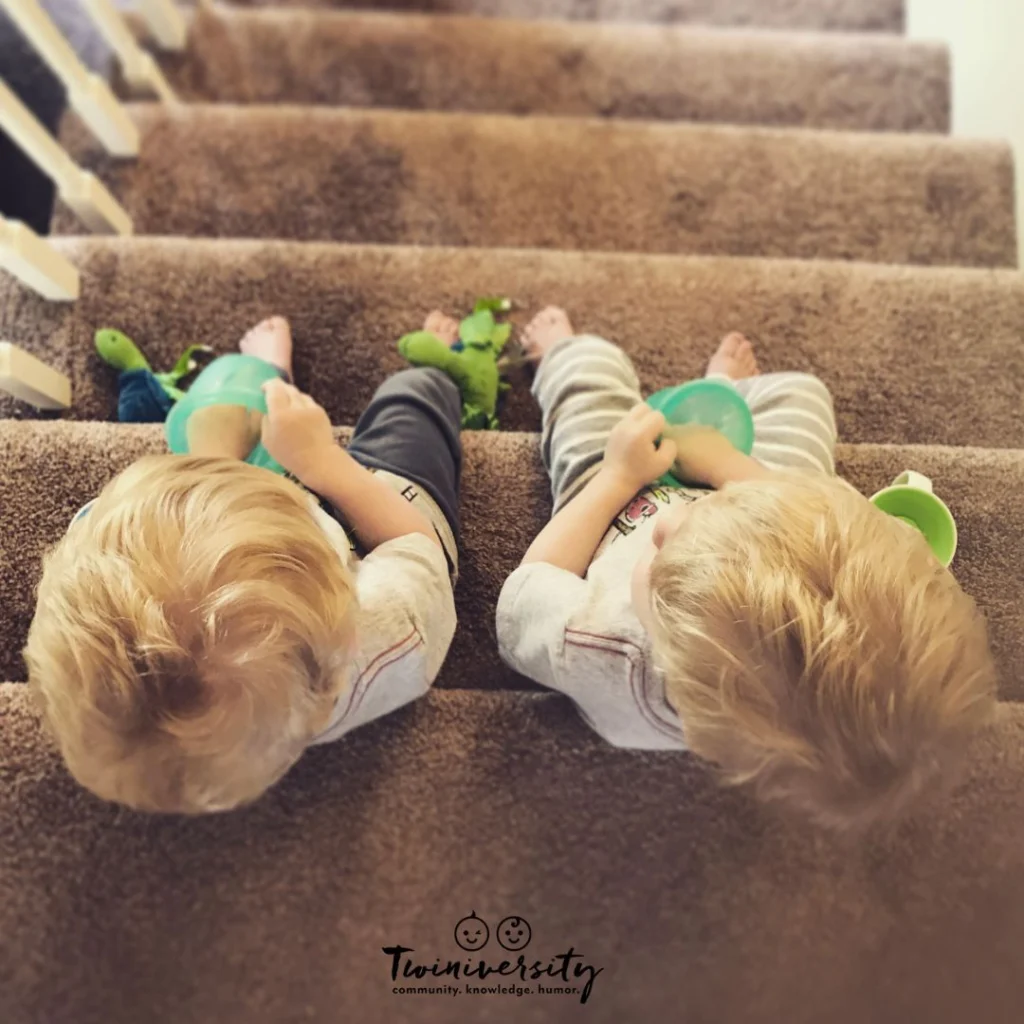 Twin toddlers sitting on the stairs eating a snack