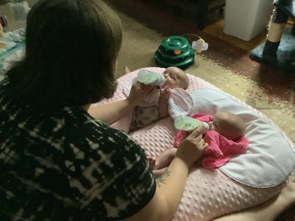 mom feeding twin girls their bottles after using double bottle warmer